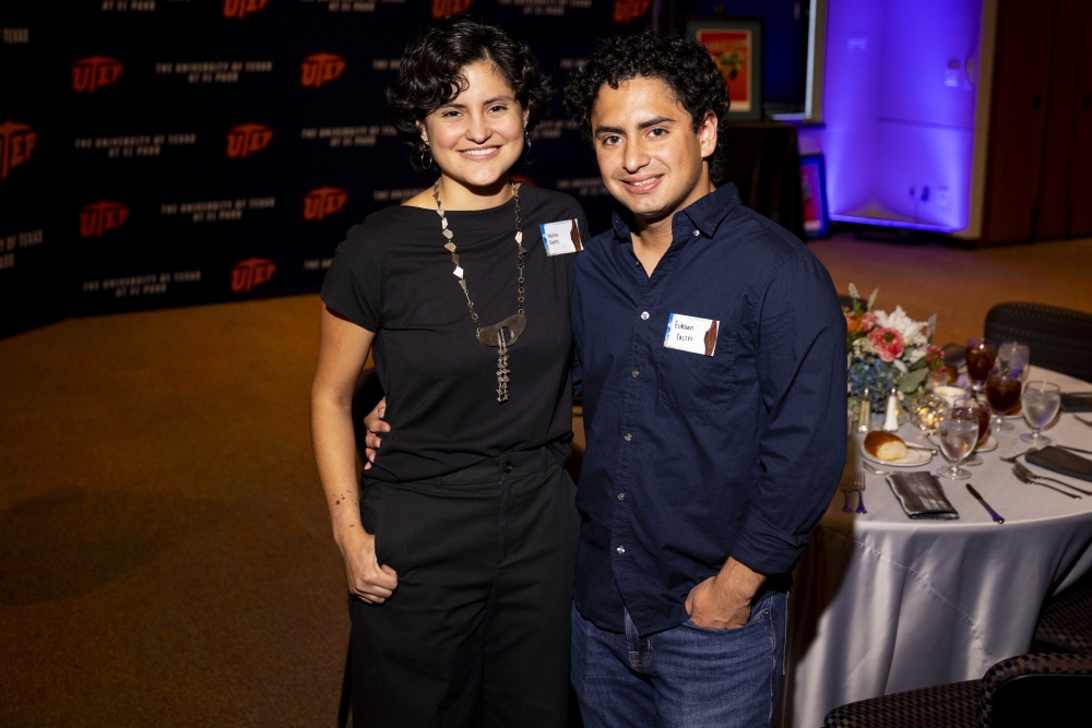 Two attendees smile for a photo beside a decorated banquet table.